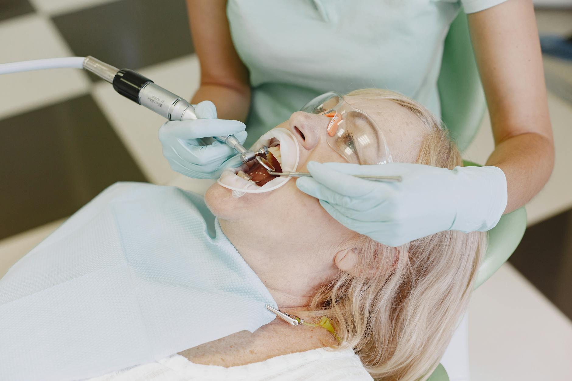 Dentist with gloves and mask examining a patient's teeth