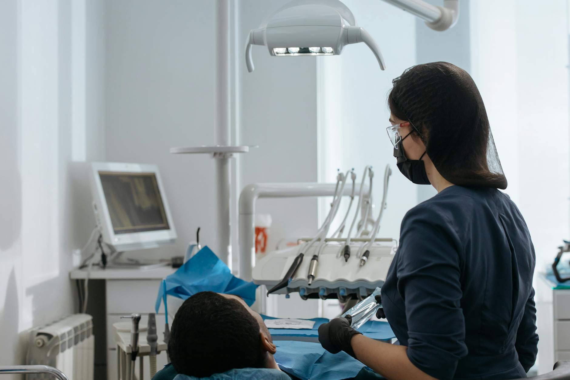 Dentist with gloves and mask examining a patient's teeth